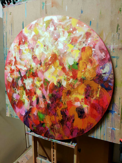 side view of Colourful abstract painting by contemporary artist Krisztina Megyeri, featuring warm reds and expressive layers of colour on a round canvas diameter 100cm